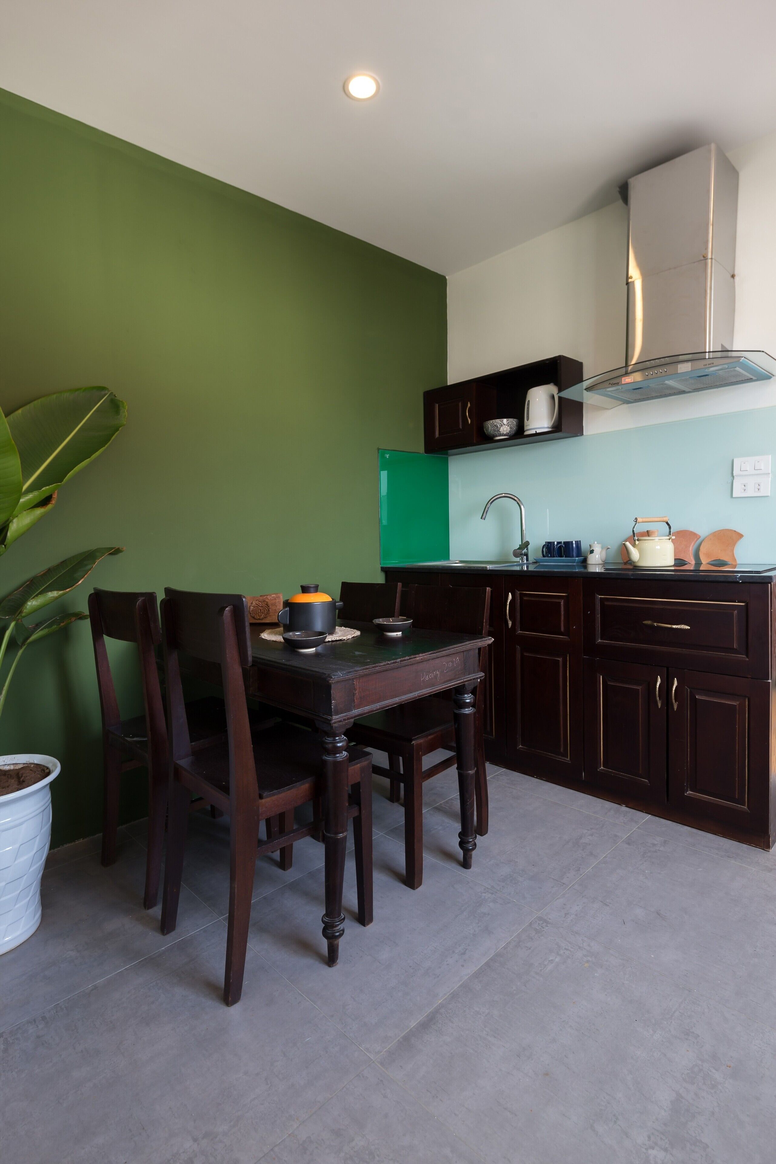 Una cocina compacta con armarios de madera oscura, pared verde y techo blanco.