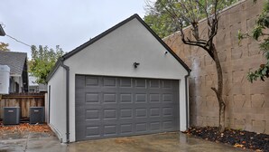 A garage with a grey door, a concrete driveway, and a brick wall.