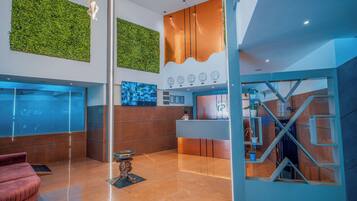 A modern lobby with a reception desk, a large wall-mounted clock, and a green wall feature.
