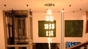 A modern interior with a unique light fixture, green wall panels, and a staircase. - HOTEL SOUTH FOREST (Sulthan Bathery)