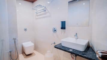 A modern bathroom with a white sink, a toilet, a shower, and a towel rack.