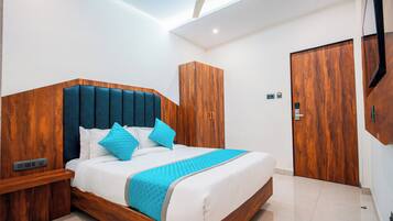 Une chambre moderne avec une tête de lit en bois, un lit avec une literie blanche et des touches de bleu, une armoire et un ventilateur de plafond.