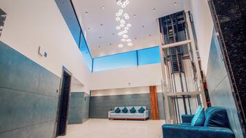A spacious lobby with a high ceiling, a central seating area, and a staircase leading to upper floors.
