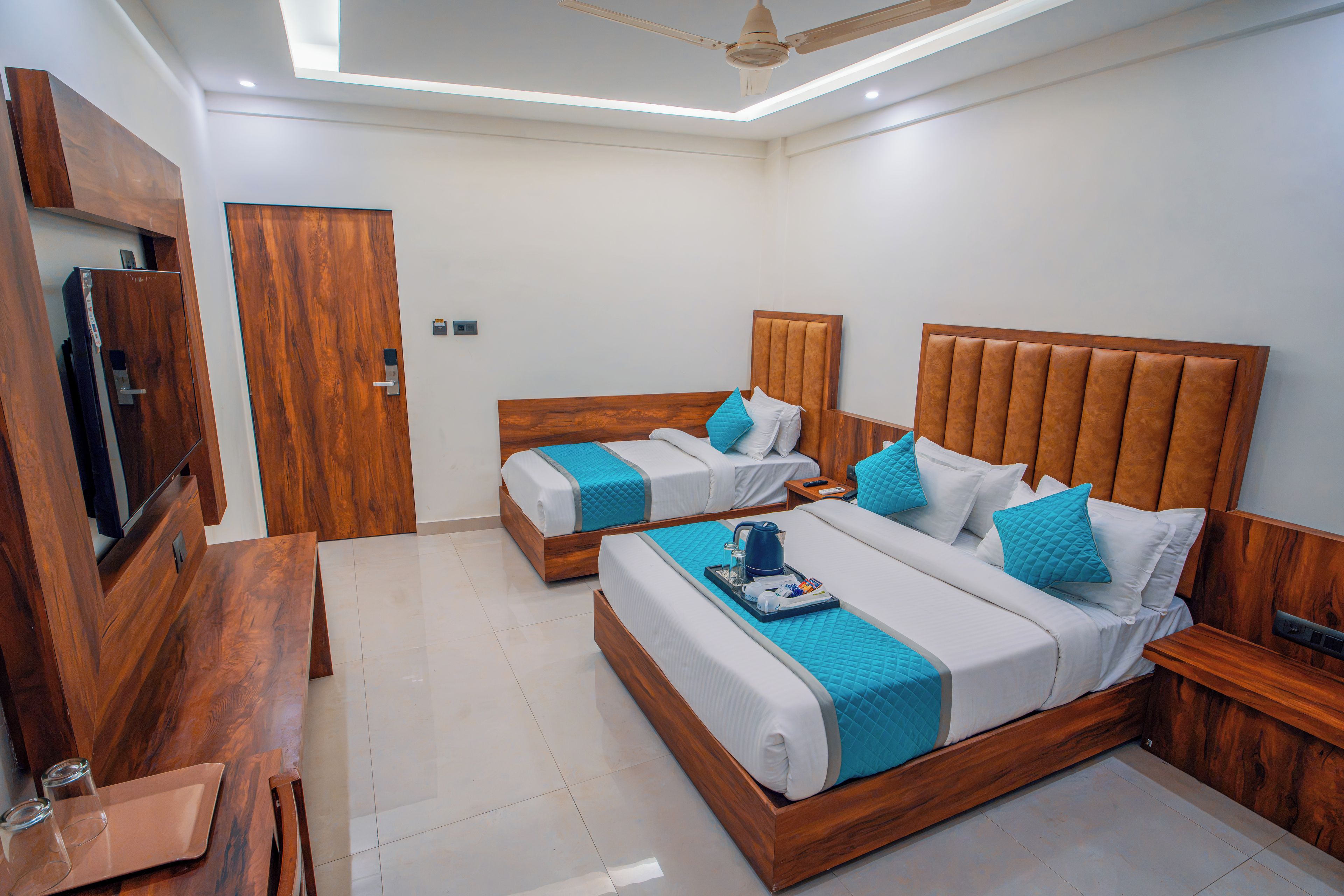 A hotel room with two beds, a TV, and a wooden desk.