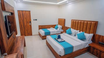A hotel room with two beds, a TV, and a wooden desk.