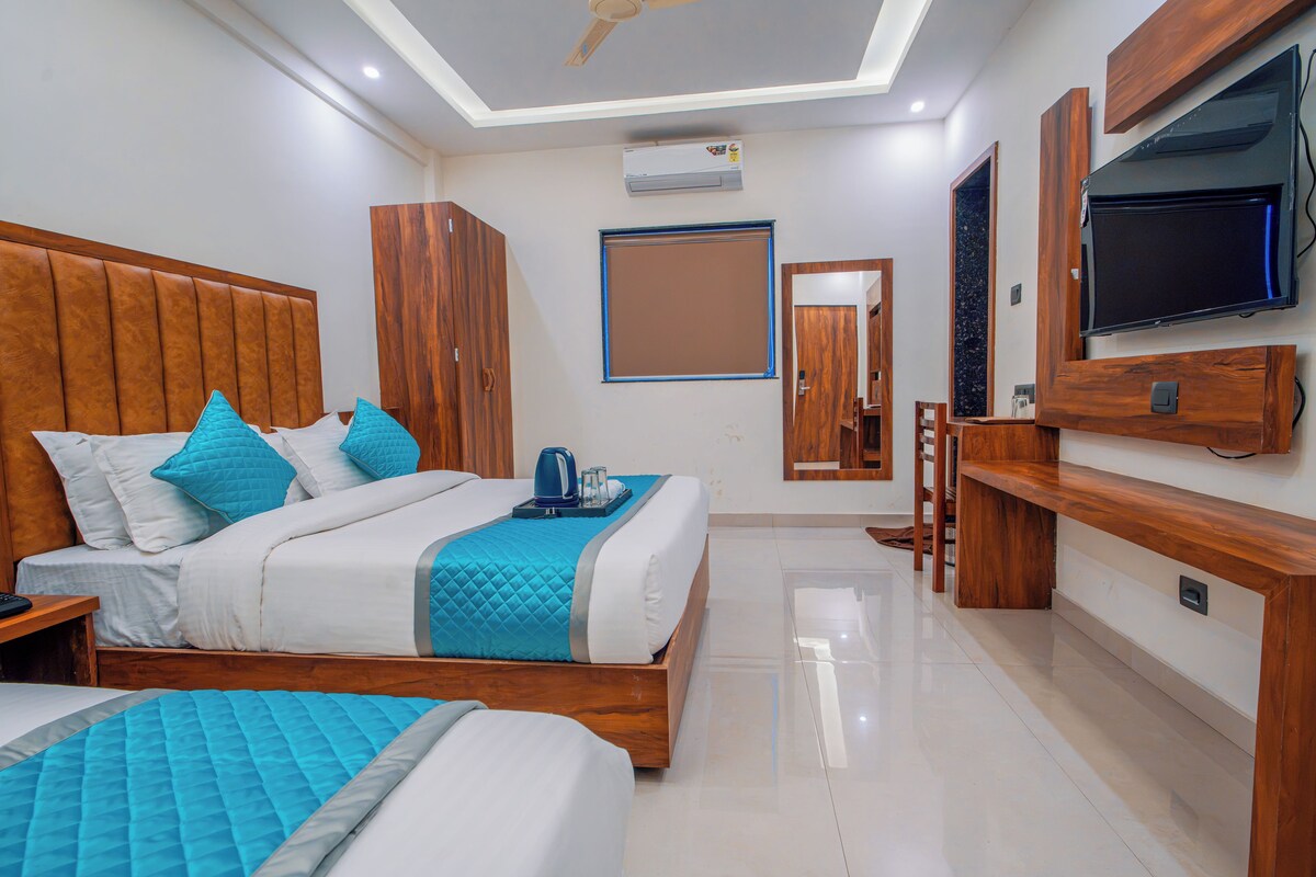 A modern hotel room with a large bed, a TV, and a minibar.