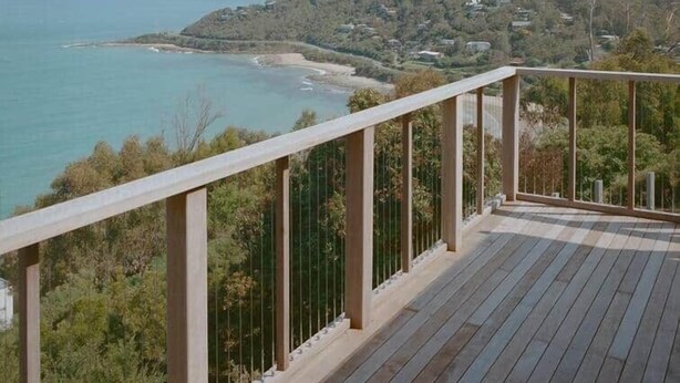 A wooden deck with a railing overlooking a coastal area with a beach and hills in the distance. - Iluka Bach - Beautiful sea views at Wye (Wye River)