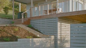 A modern house with a covered porch, a wooden deck, and a landscaped garden. - Iluka Bach - Beautiful sea views at Wye (Wye River)