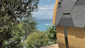 A view of a building with a hexagonal roof and a wooden exterior, overlooking a coastal landscape with trees and the sea. - Iluka Bach - Beautiful sea views at Wye (Wye River)