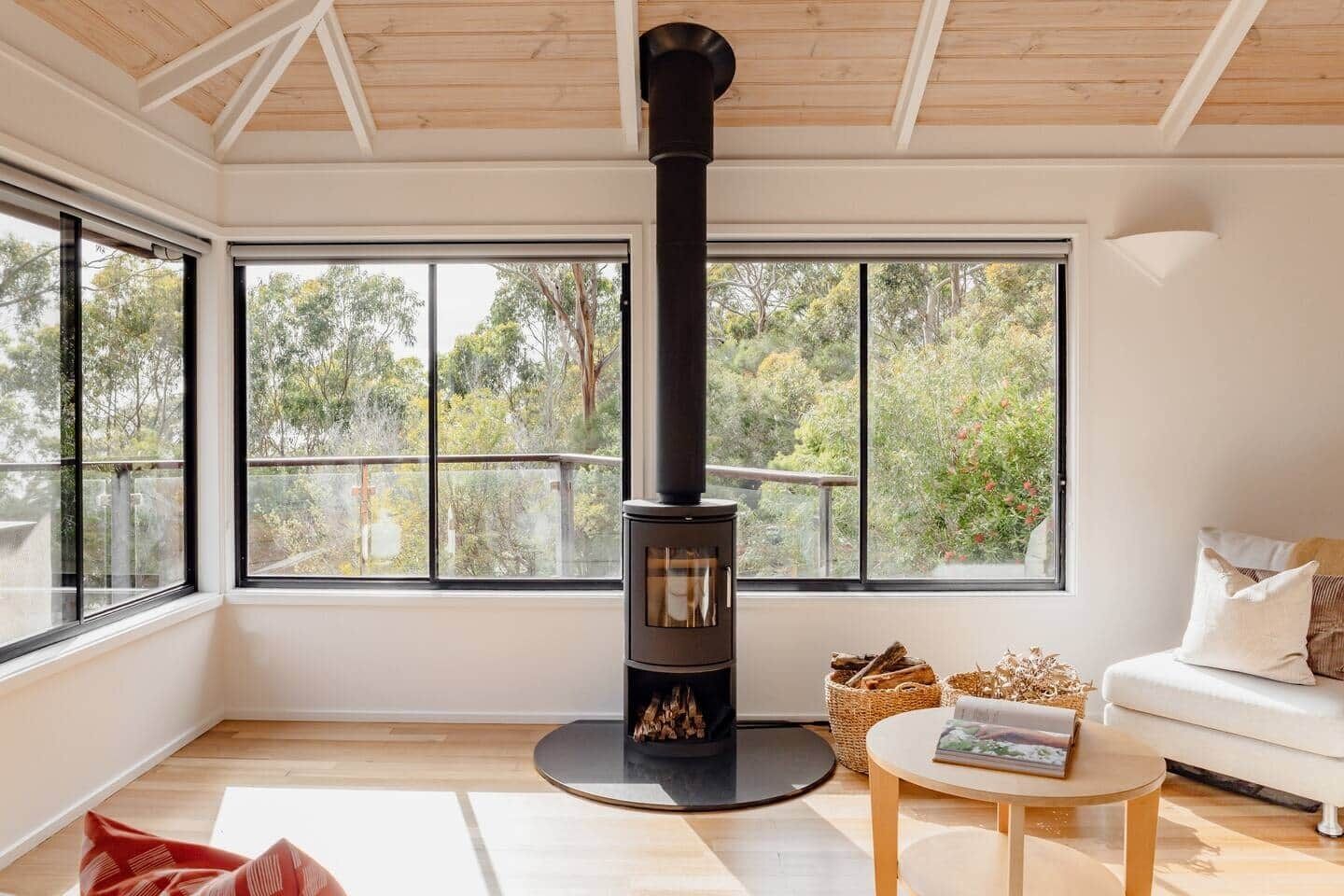 A modern living room with a wood-burning stove, large windows, and a cozy seating area.