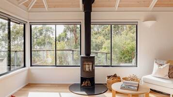 A modern living room with a wood-burning stove, large windows, and a cozy seating area.