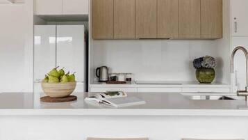 A modern kitchen with wooden cabinets, a white countertop, and three wooden stools.