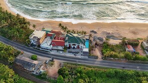 An aerial view of a coastal area with a road, buildings, and a beach. - AIDA The Queen Palace (Induruwa)