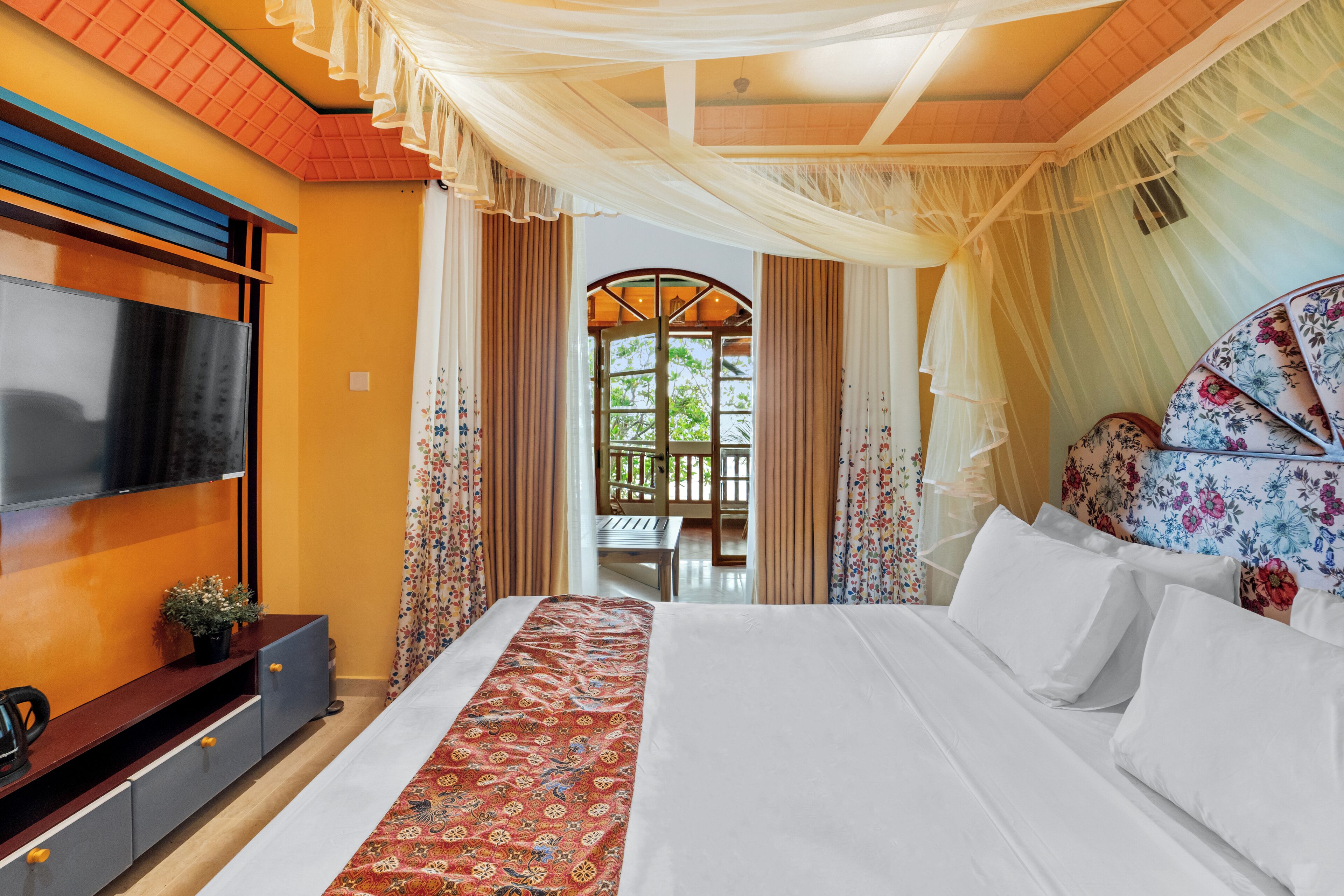 Un dormitorio con una cama grande, un televisor montado en la pared y vistas al exterior a través de una ventana.