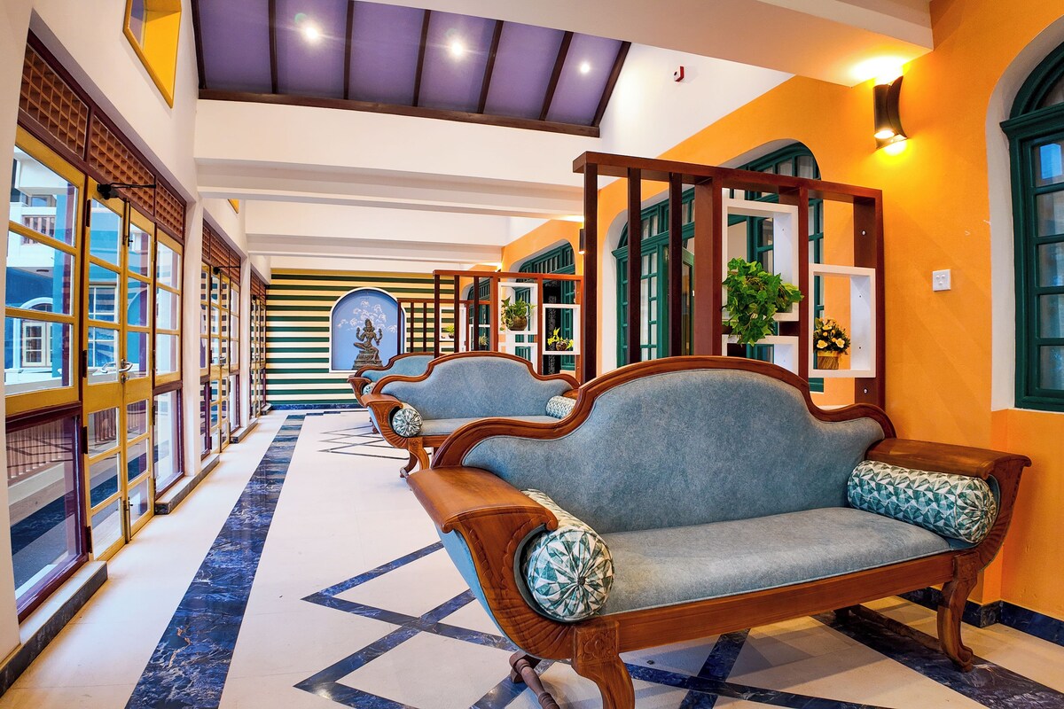 A hallway with traditional wooden furniture, a patterned floor, and a view of the outside through large windows.