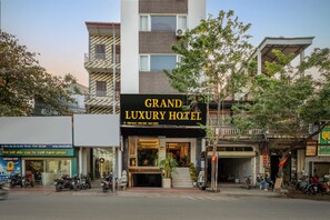 A hotel with a prominent sign, a staircase leading to the entrance, and several parked motorcycles. - Grand Luxury Hotel (Phu Khe)