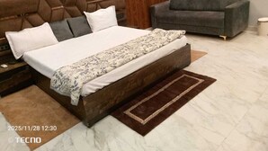 Une chambre à coucher avec un grand lit, un canapé gris et une tête de lit en bois.