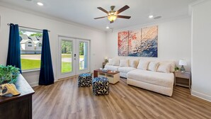 Sala de estar com sofá, pufes, mesa de centro e ventilador de teto.