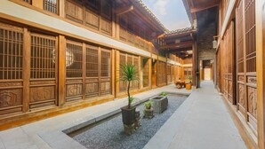 A traditional courtyard with wooden buildings, a small water feature, and potted plants. - Li River Craftsman Village  Guilin (Guilin)