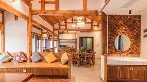 A spacious room with wooden beams, a dining area, and a bathroom with a wooden vanity and a mirror. - Li River Craftsman Village  Guilin (Guilin)