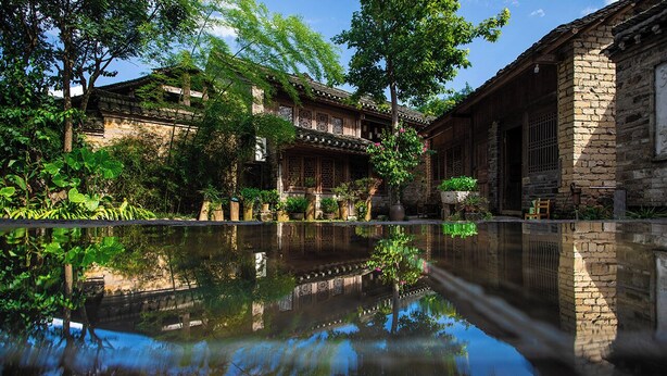 A traditional courtyard with a reflective water surface, stone buildings, and lush greenery. - Li River Craftsman Village  Guilin (Guilin)