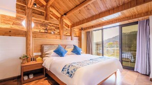 A wooden cabin-style bedroom with a large bed, wooden headboard, and a view of the outdoors through a sliding glass door. - Li River Craftsman Village  Guilin (Guilin)