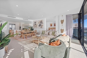 Ein modernes Wohnzimmer mit Essbereich, Küche und Balkon mit Blick auf die Stadt.