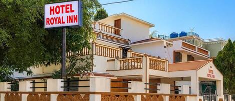 A hotel named Royal Inn with a signboard, a multi-story building with balconies, and a gated entrance.