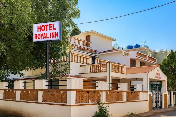 A hotel named Royal Inn with a signboard, a multi-story building with balconies, and a gated entrance.