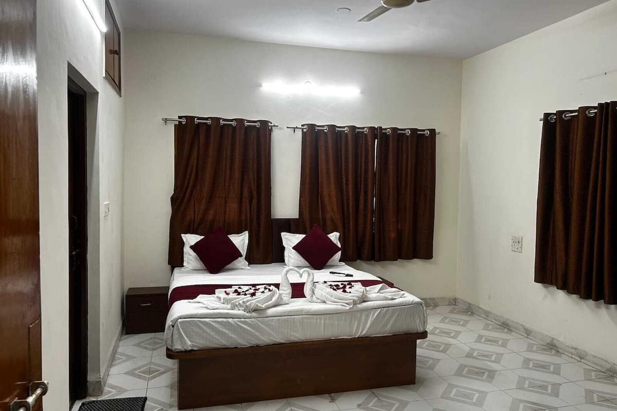 A bedroom with a bed, curtains, a ceiling fan, and a tiled floor.