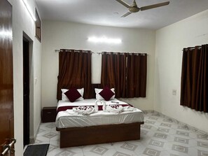 A bedroom with a bed, curtains, a ceiling fan, and a tiled floor.