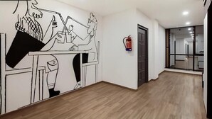 A hallway with a wooden floor, a fire extinguisher on the wall, and a door leading to another room. - Hotel Royal Inn (Pune)