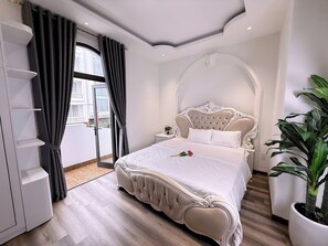 A bedroom with a large bed, a wardrobe, a potted plant, and a view of the outside. - Sweet Home Hotel & Apartment (Da Nang)