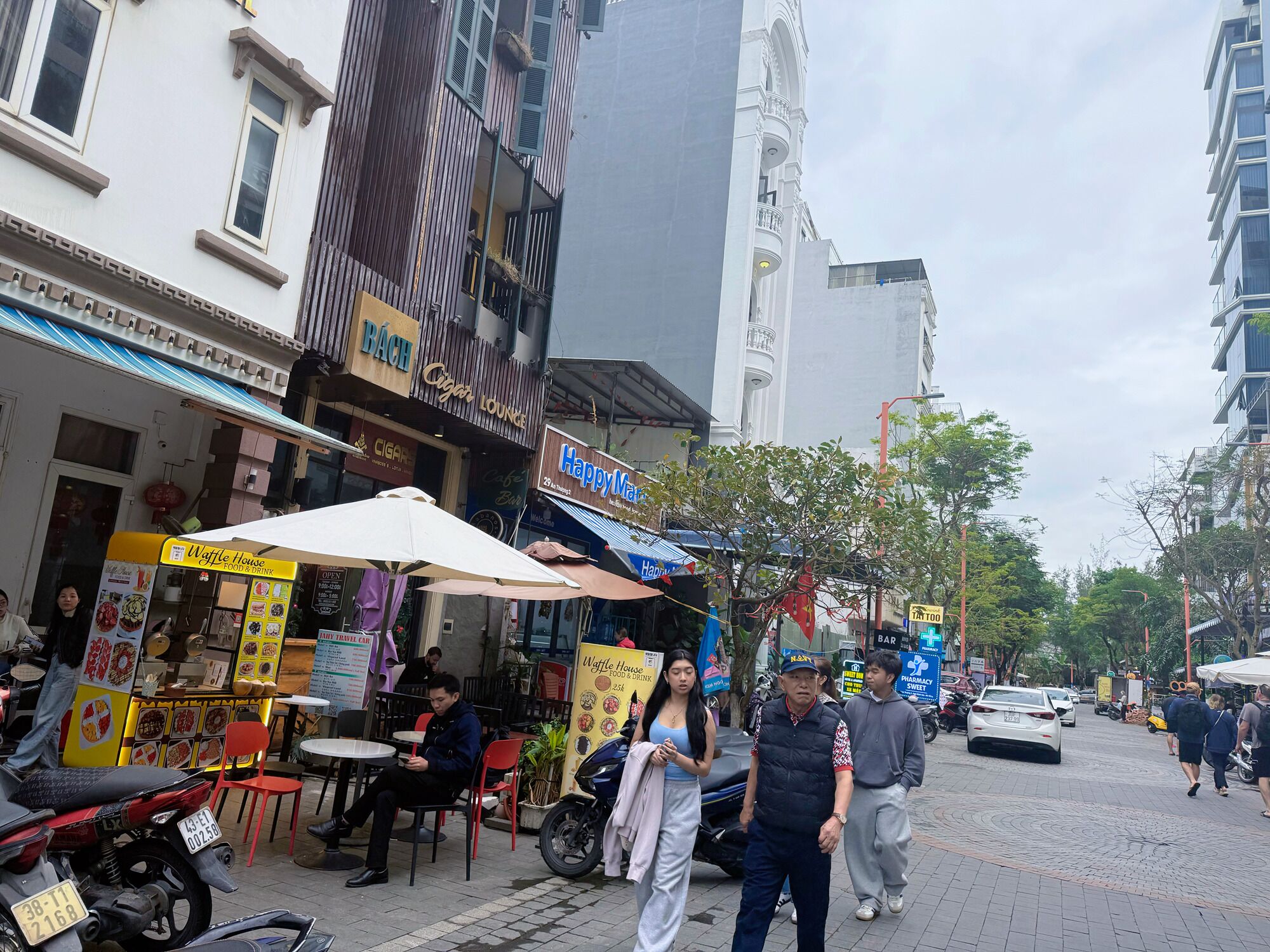 A street with various shops, including a Waffle House and a cigar lounge.