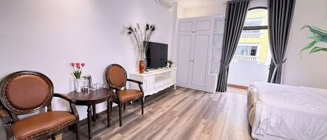 A hotel room with a bed, a TV, a desk with a chair, and a wardrobe.