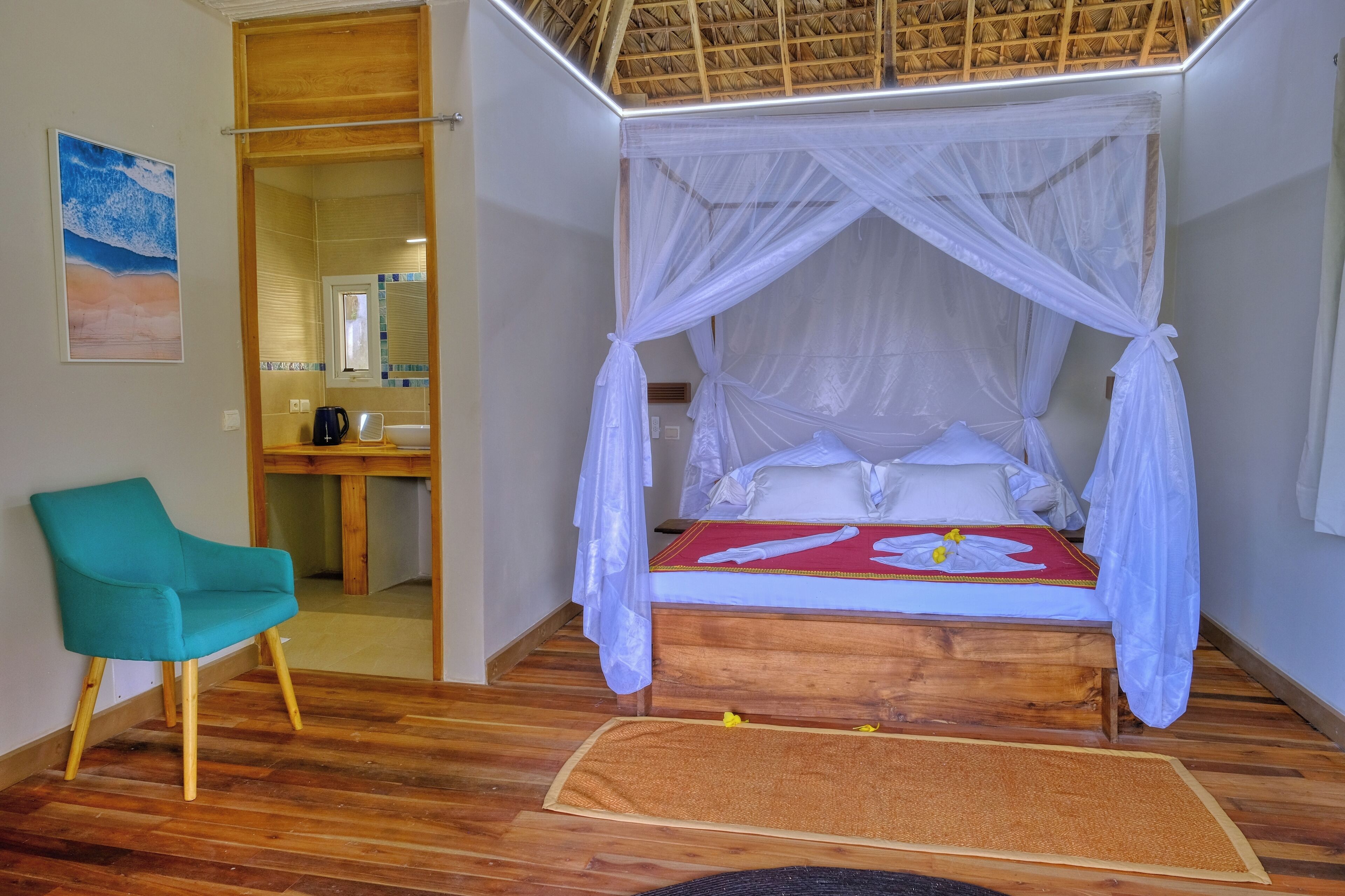 Una habitación con una cama de madera, una silla verde azulada y un escritorio de madera.