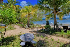 Un jardín tropical con una gran estatua de tortuga, palmeras y vista al mar.