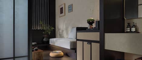 A modern, minimalist room with a sofa, a small table, a potted plant, and a mirror.