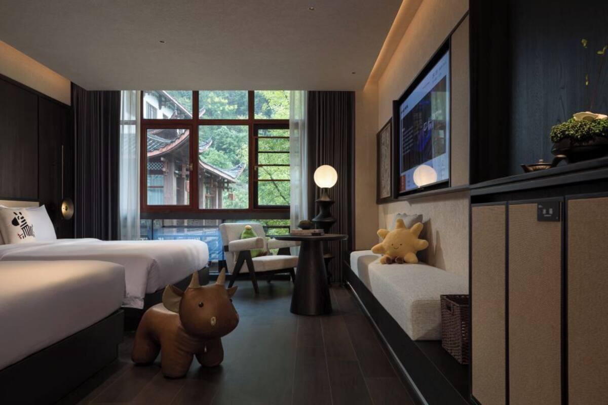 Une chambre d’hôtel avec deux lits, un canapé, une petite table et un téléviseur.