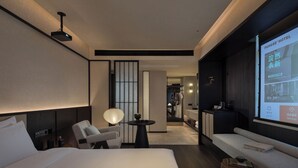 A modern hotel room with a large bed, a seating area, a TV screen displaying hotel services, and a view into the room's interior. - FunGee S Hotel Zhangjiajie National Park (Zhangjiajie)