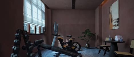A gym with exercise equipment, a treadmill, and a large window with blinds.