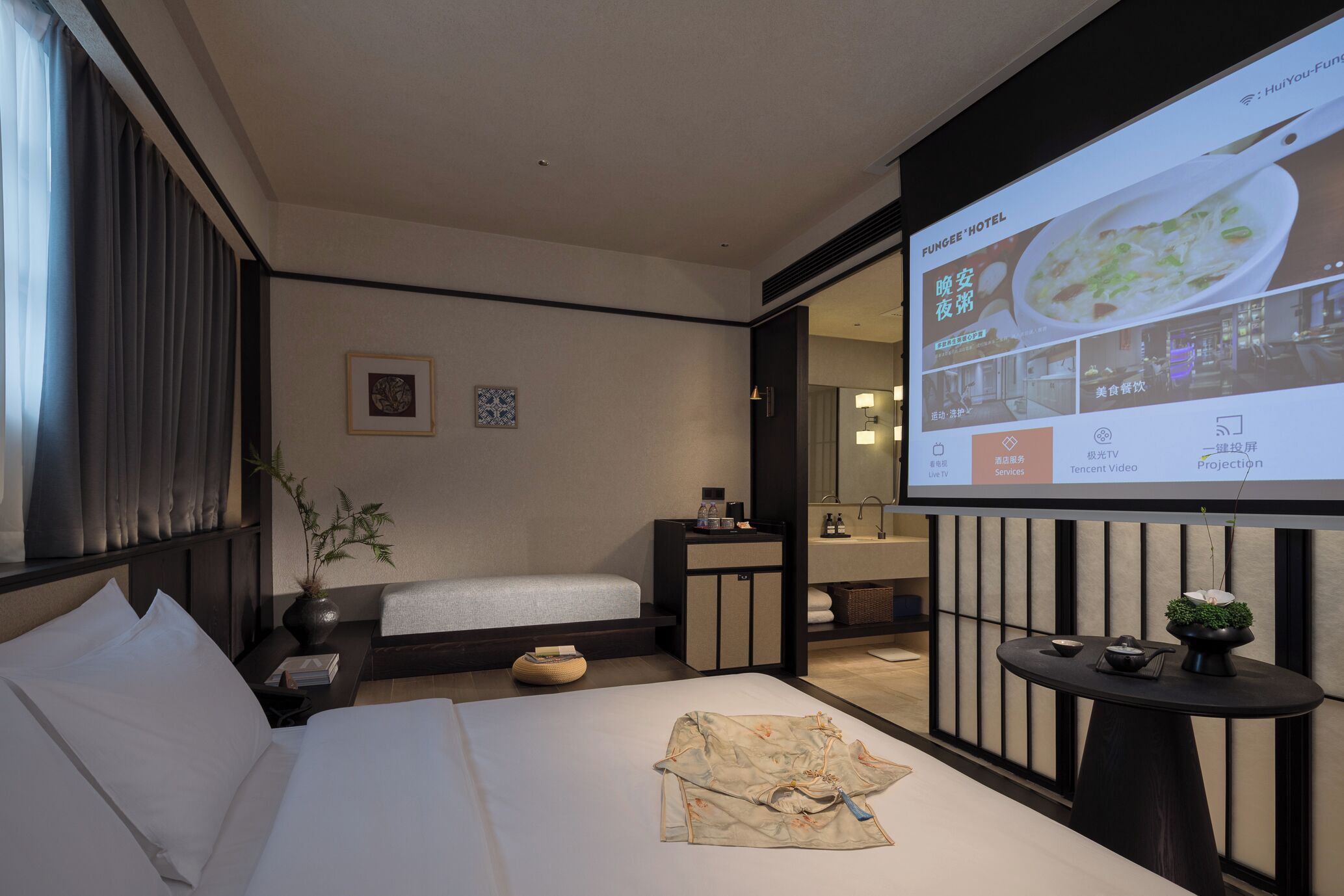 A hotel room with a bed, bedside table, and a projection screen displaying hotel amenities.