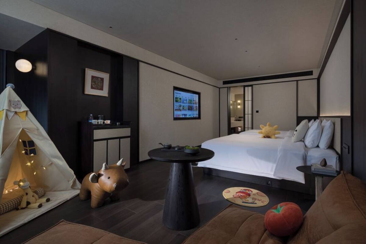 Une chambre d’hôtel moderne équipée d’un lit, d’une petite table, d’une tente et d’un téléviseur qui affiche un menu.