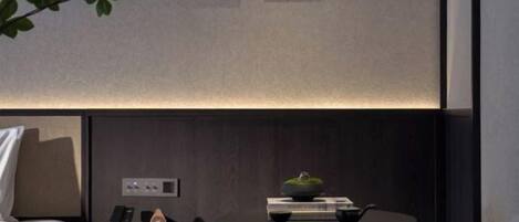 A modern hotel room with a bed, a seating area with a table, and two framed artworks on the wall.