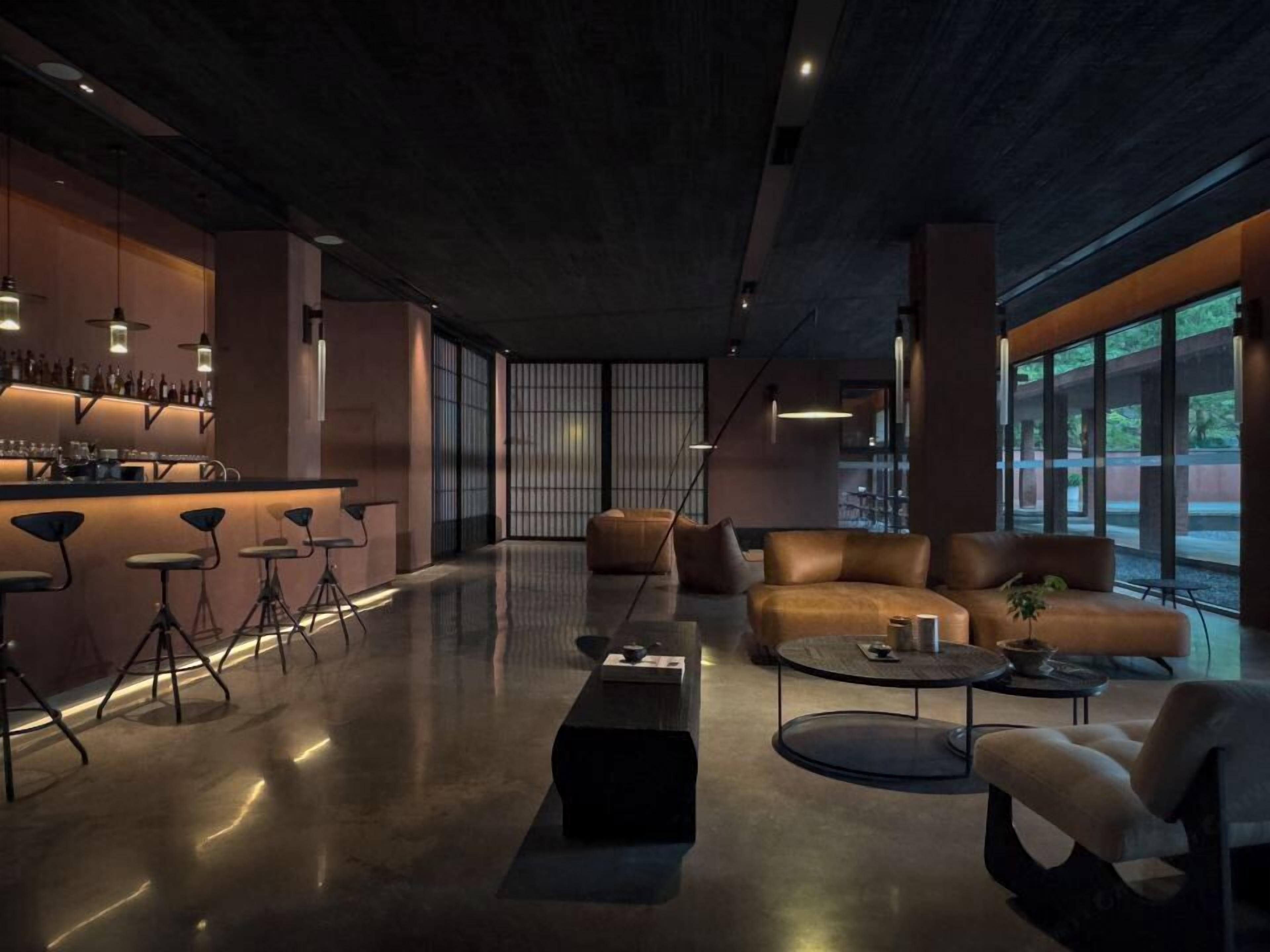 A modern lounge area with a bar, seating, and large windows.