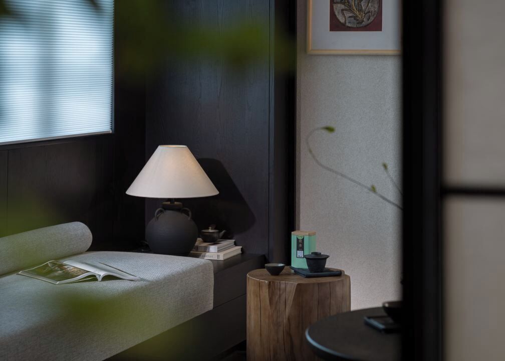A modern room with a sofa, a table, a lamp, and a small wooden stool.