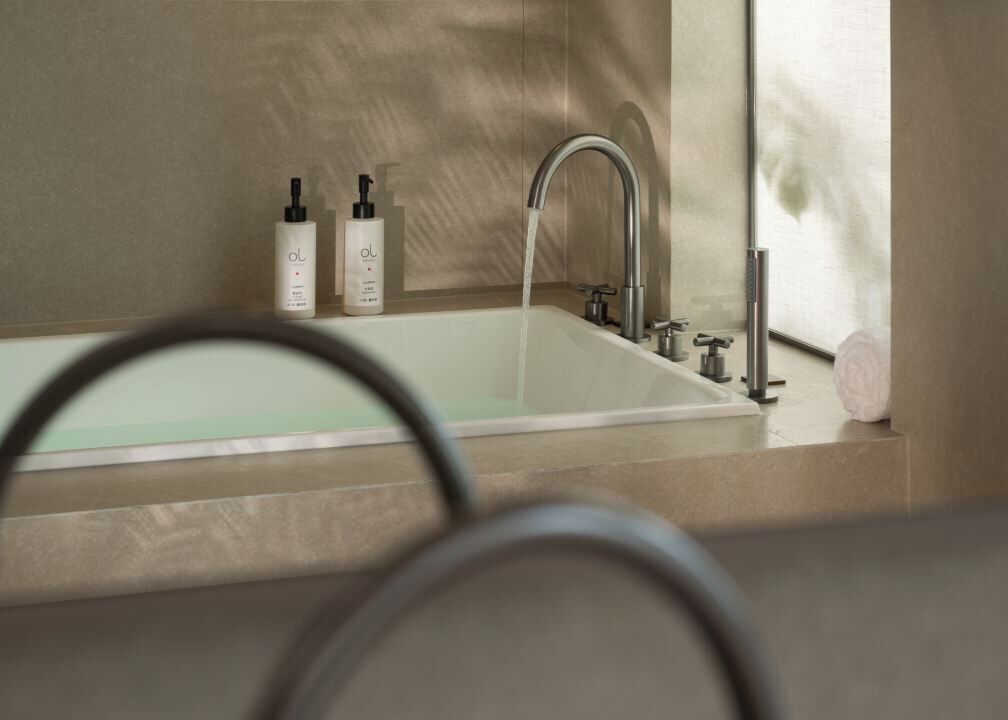 A modern bathroom with a bathtub, a faucet, and two bottles of lotion on the counter.