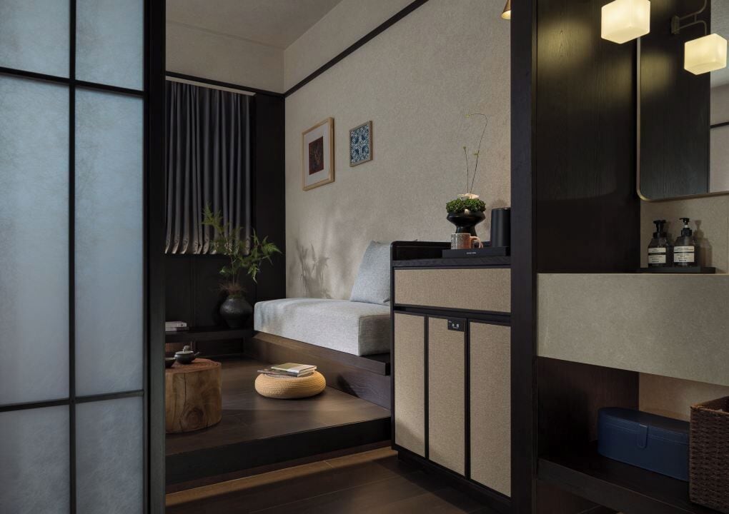 A modern, minimalist room with a sofa, a small table, a plant, and a mirror.