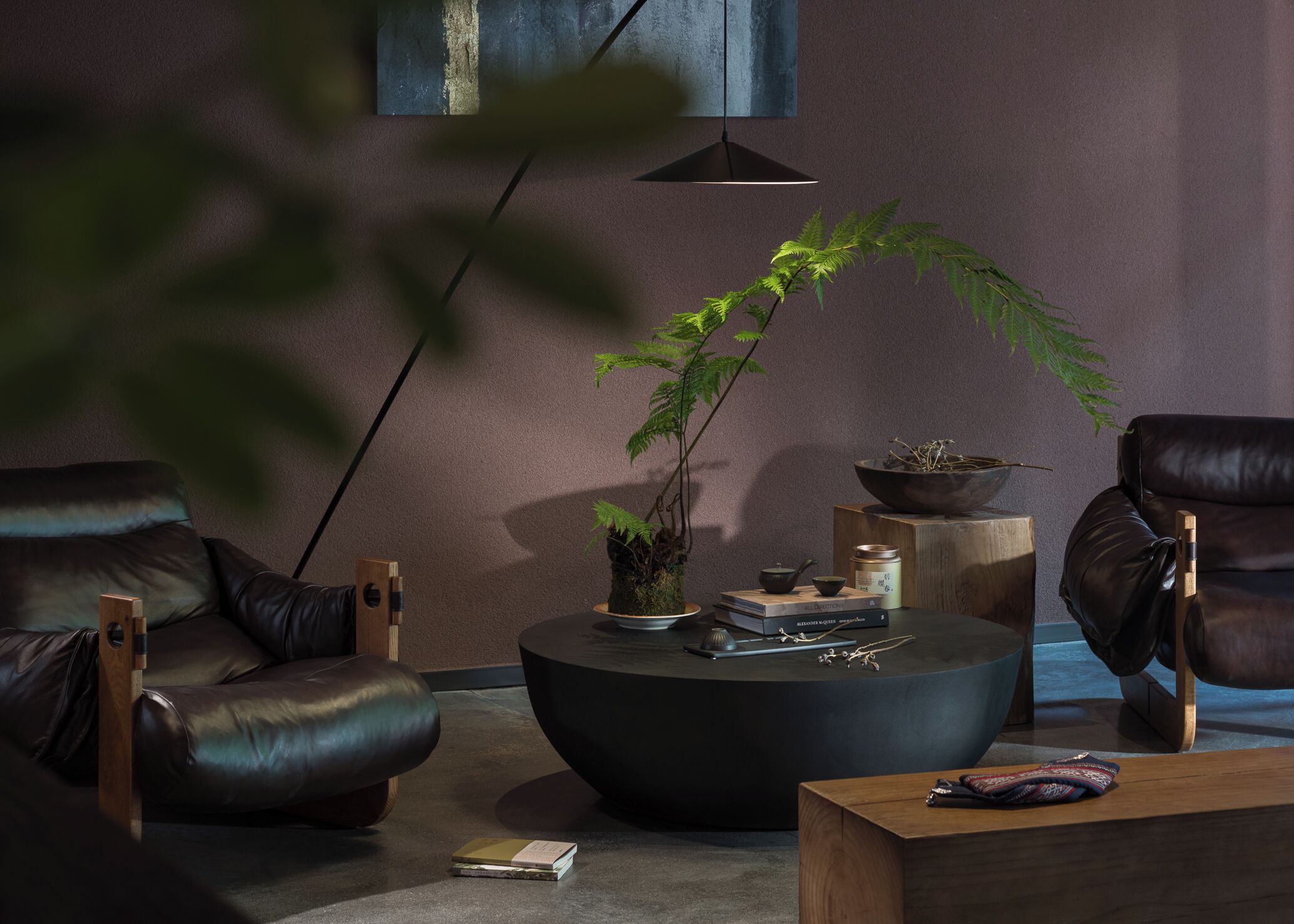 Una sala de estar moderna con un sofá de cuero, una mesa de centro redonda y una planta en maceta.