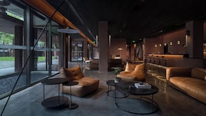 A modern lounge area with leather sofas, round tables, and a large window providing a view of the outdoors. - FunGee S Hotel Zhangjiajie National Park (Zhangjiajie)